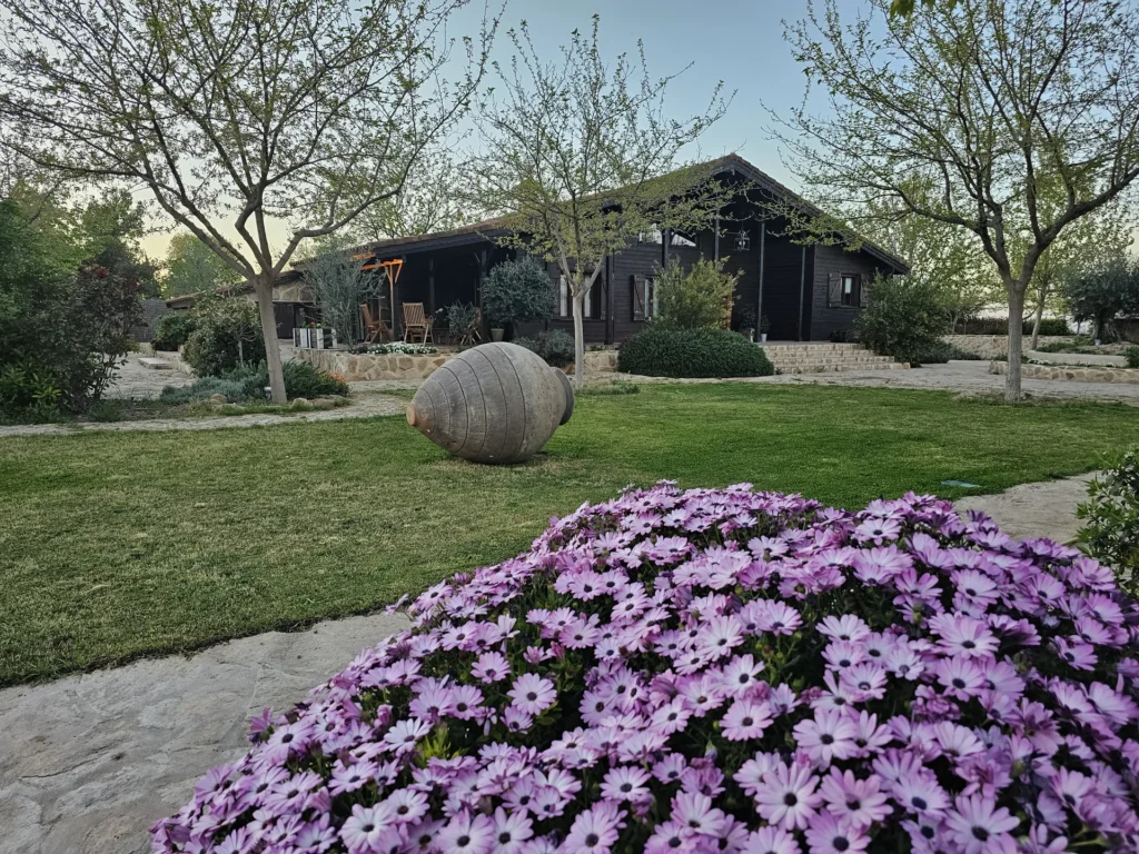 Casa rural de madera con jardín y flores moradas