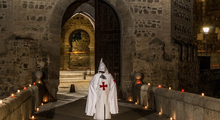 Escena de una ruta nocturna con una figura vestida de blanco y velas